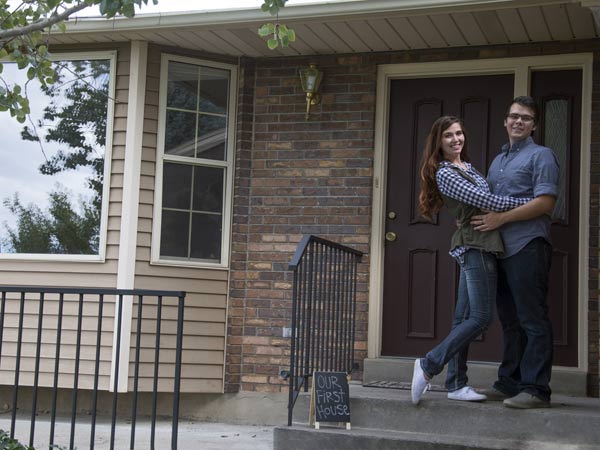 happy couple posing in front of home